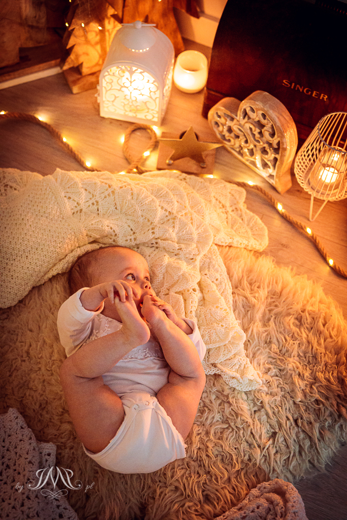 noworodek zagladający na światełka bożonarodzeniowe w domu