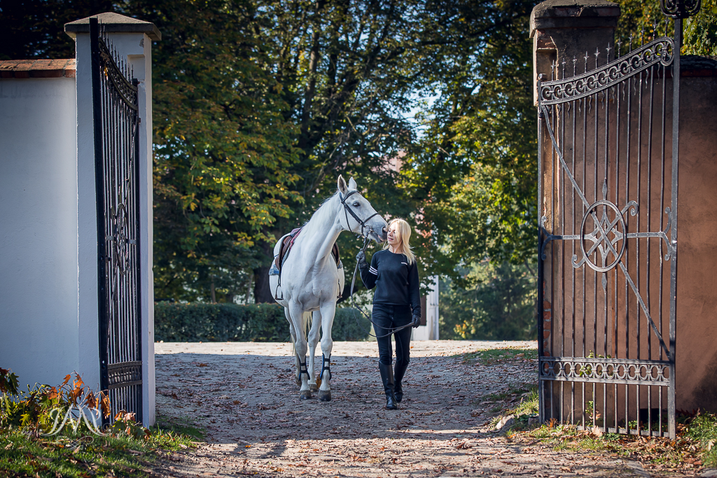 kobieta prowadząca konia przez bramę